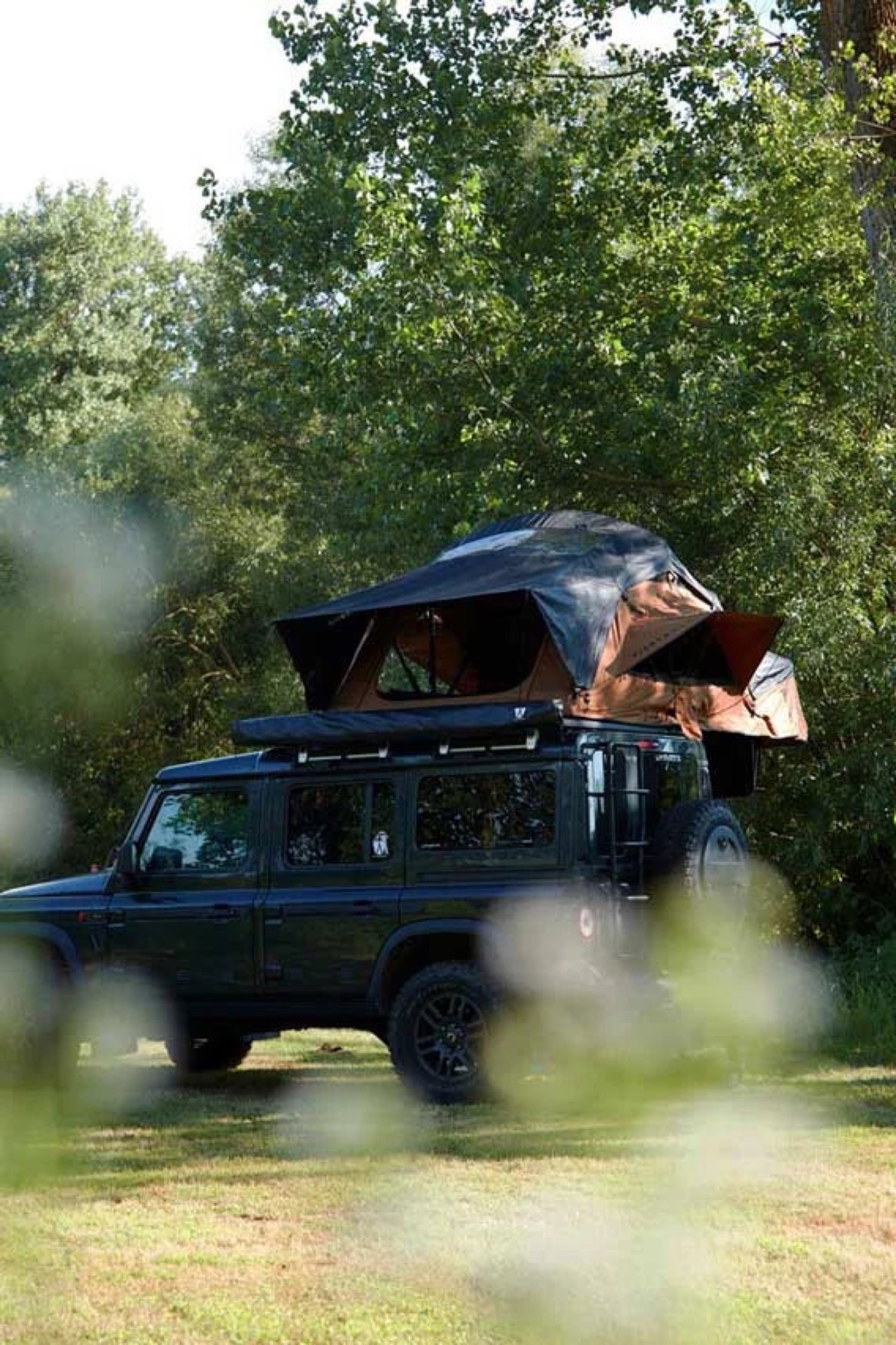 Geländewagen mit Dachzelt und Vorzelt im Wald